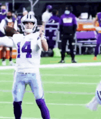 a football player wearing a white and purple uniform is standing on a field .