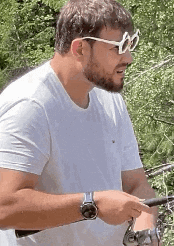 a man with a beard wearing sunglasses is holding a fishing rod .