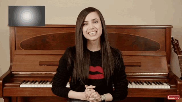 a woman sitting in front of a piano with a subscribe button on the bottom