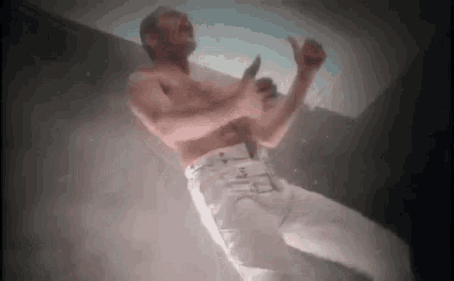 a shirtless man is floating in the air with his arms outstretched in a dark room .