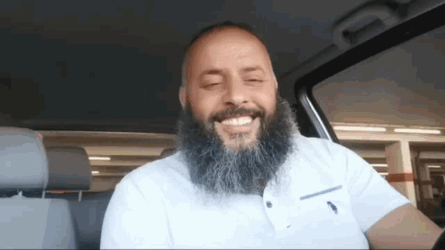 a man with a beard wearing a polo shirt is smiling