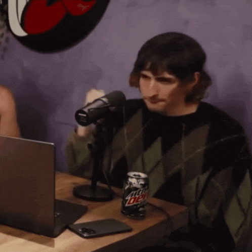 a man sitting in front of a microphone with a can of mountain dew