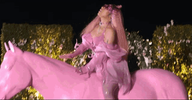 a woman in a pink dress is riding a pink unicorn