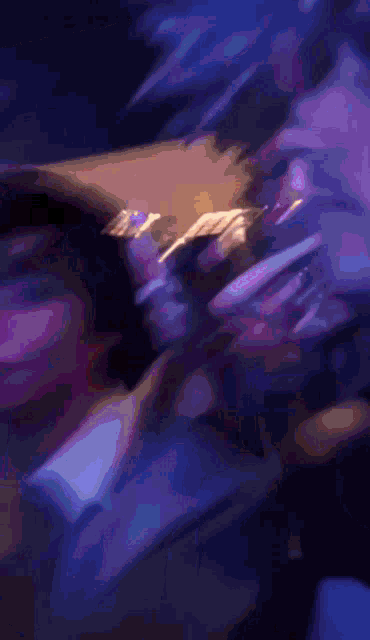 a blurry image of a person 's face with purple lights behind them