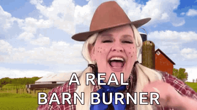 a woman in a cowboy hat says a real barn burner in front of a barn