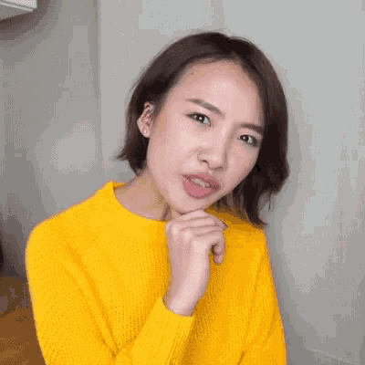 a woman wearing a yellow sweater is making a funny face and the word no is on her face