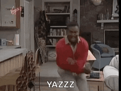 a man in a red sweater is dancing in a living room while sitting on a couch .