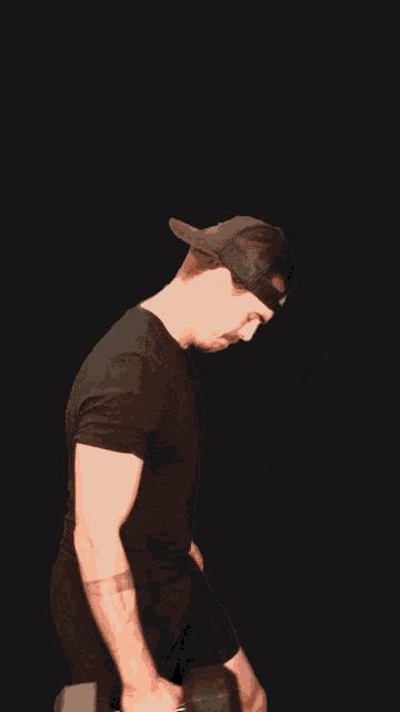 a man wearing a black hat is holding a dumbbell