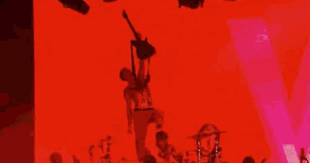 a man is hanging upside down from a guitar while playing drums .