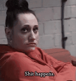 a woman in a red shirt is sitting on a couch .