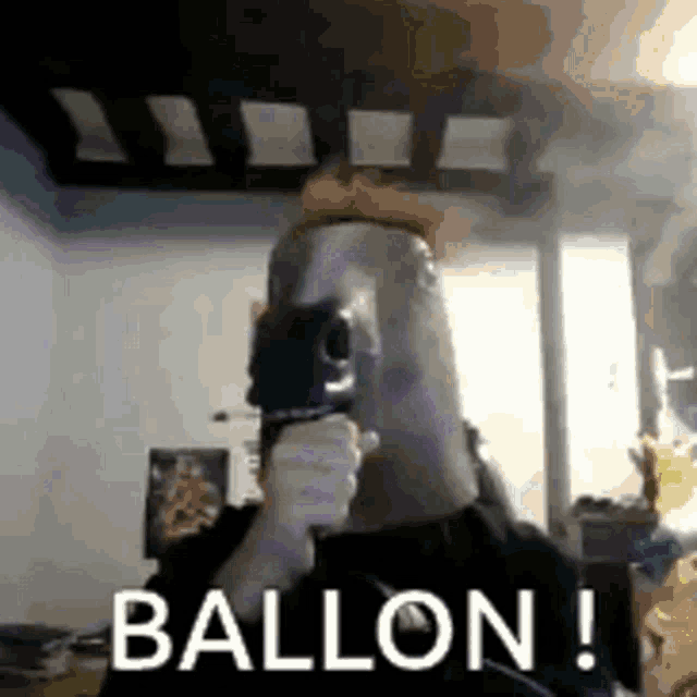 a man is holding a gun in front of his face with the words ballon written on the bottom .