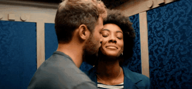 a man is kissing a woman on the cheek in a dressing room
