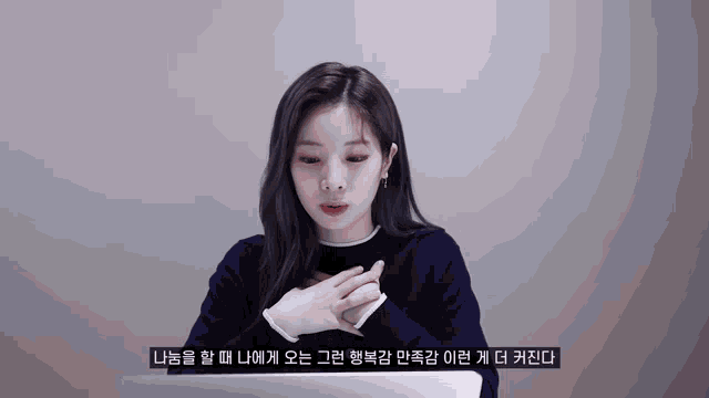 a woman sitting in front of a laptop with korean writing on the bottom right