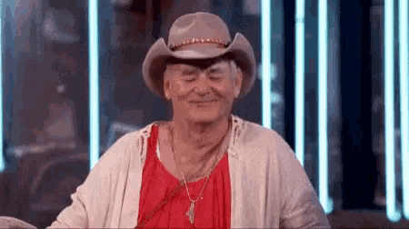 a man wearing a cowboy hat and a red shirt is laughing .