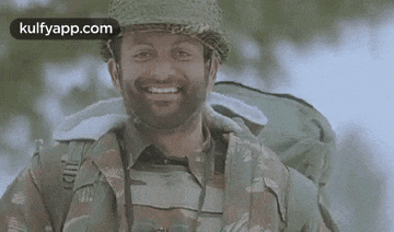 a man in a military uniform is smiling while holding binoculars .