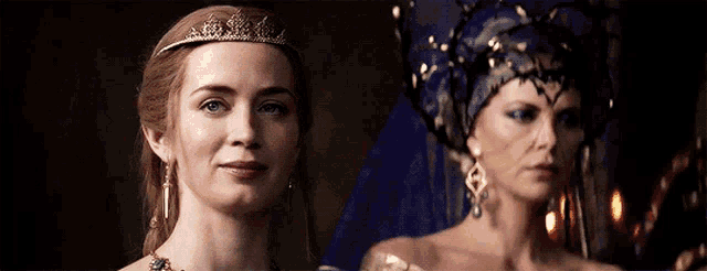 a woman wearing a tiara is standing next to another woman wearing a blue hat .