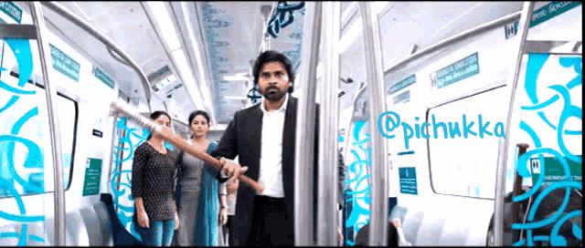 a man in a suit holds a stick in a subway car with the name pichukka written on the bottom