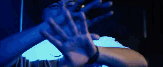 a man is covering his face with his hands in a dark room