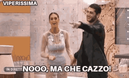 a man and a woman are standing next to each other in a room and the man is pointing at the woman .