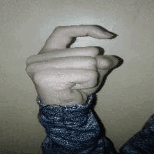 a person 's hand is making a fist with their thumb and index finger .