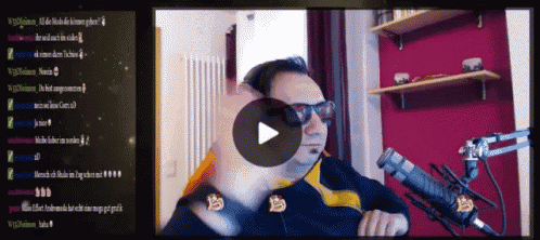 a man wearing sunglasses is sitting in front of a microphone with a play button in front of him