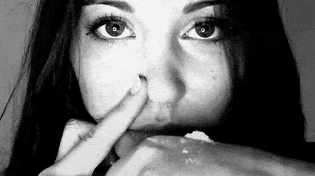 a black and white photo of a woman eating a piece of cake .