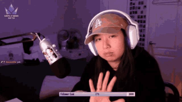 a woman wearing headphones and a la hat is giving a high five