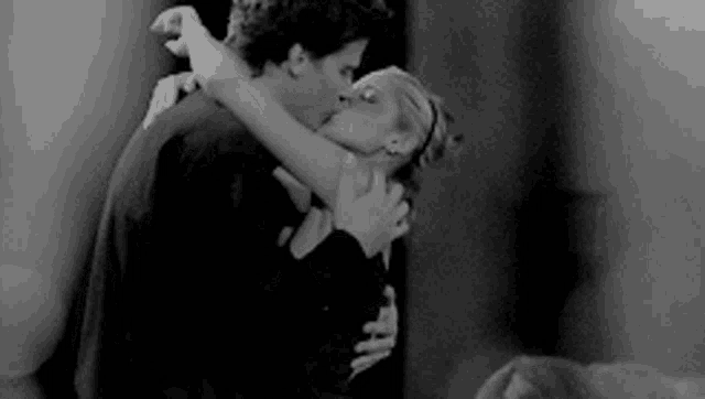 a man and a woman are hugging and kissing in a black and white photo .