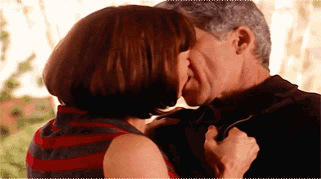 a man and a woman are kissing in a room