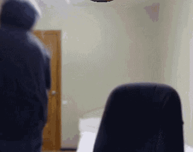 a blurry picture of a man in a hoodie standing in a room