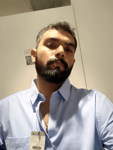 a man with a beard wears a light blue shirt with a tag that says ca on it