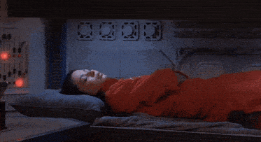 a man in an orange jumpsuit is laying on a bunk bed in a spaceship
