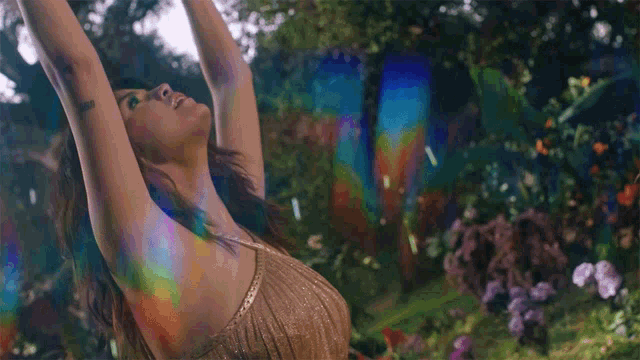 a woman in a gold dress is dancing in a garden