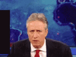 a man in a suit and tie is standing in front of a screen