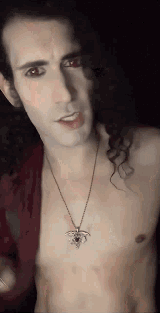 a shirtless man with long curly hair wearing a necklace