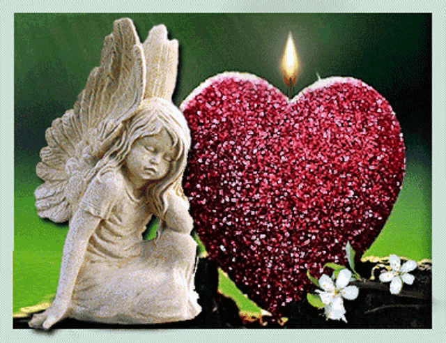 a statue of a girl with wings sits next to a heart shaped candle