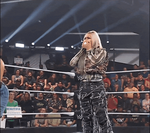 a woman is standing in a wrestling ring with a sign that says beautiful