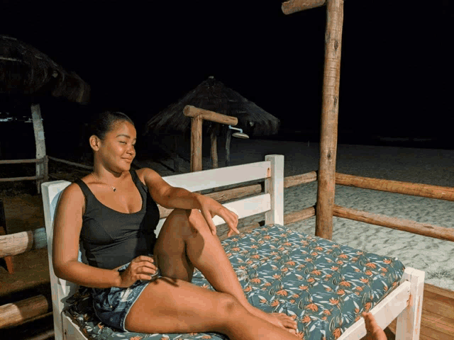 a woman sits on a bed with her legs crossed in front of the beach