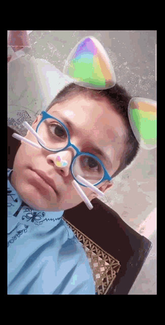 a young boy wearing glasses and cat ears is making a funny face