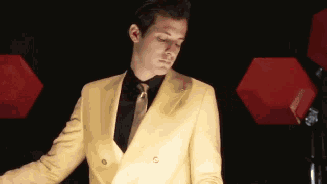 a man wearing a yellow suit and black shirt