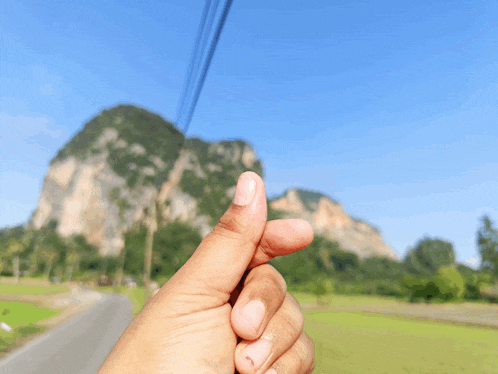 a person 's hand is making a heart shape with their thumb