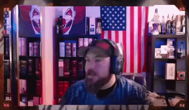 a man wearing headphones and a hat is sitting in front of an american flag