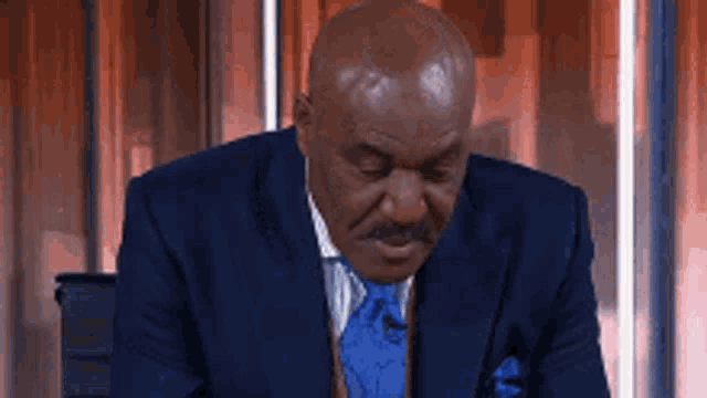 a man in a suit and tie is sitting in a chair with his head down .
