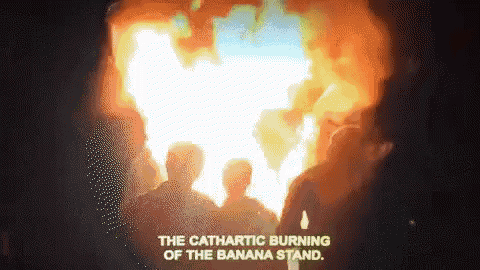 a group of people standing in front of a large fire with the words " the cathartic burning of the banana stand " below them