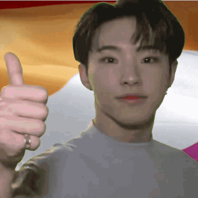 a young man with a ring on his finger gives a thumbs up sign