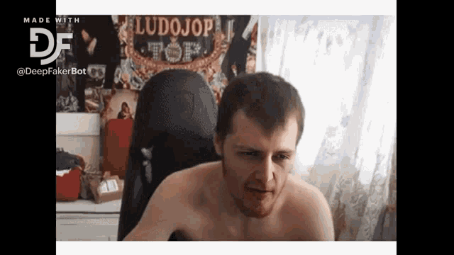 a shirtless man is sitting in front of a poster that says ludojop top