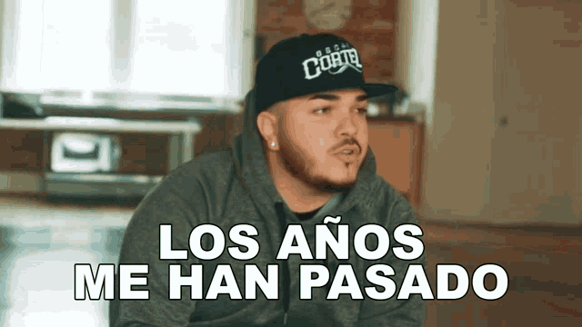 a man with a beard wearing a black hat that says los anos me han pasado