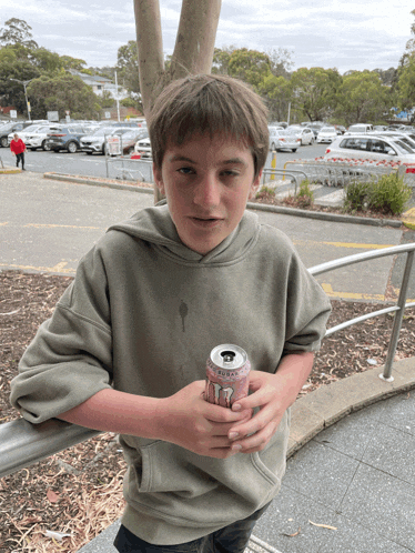 a young boy holds a can of t7 energy drink in his hands