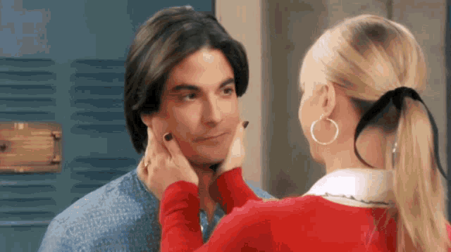 a woman is touching a man 's face with her hand