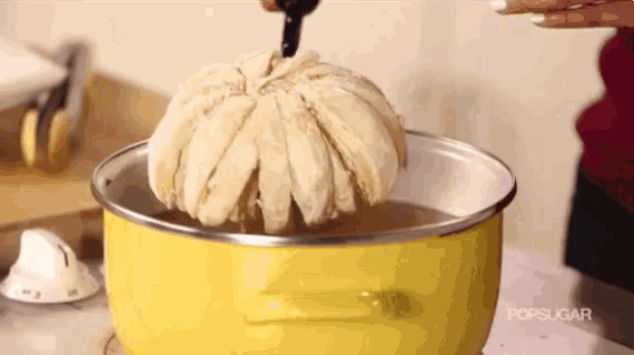 a yellow pot filled with water and a large piece of bread on top of it .